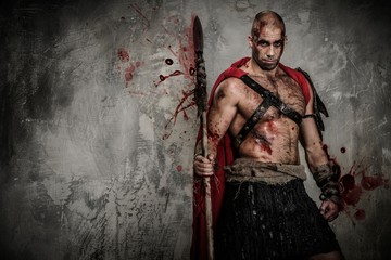 Fototapeta na wymiar Wounded gladiator in red coat holding spear
