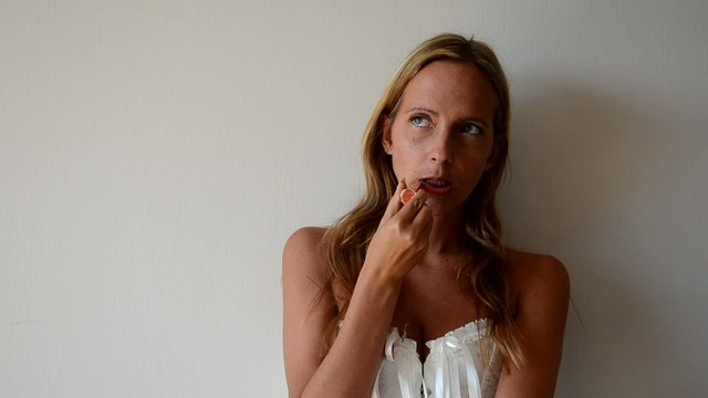 Femme en corset se mettant du rouge &agrave; l&egrave;vres