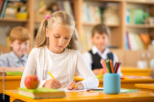 Little schoolgirl sitting behind school desk