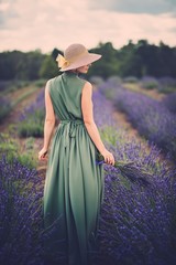 Woman in long green dress and hat in a lavender field