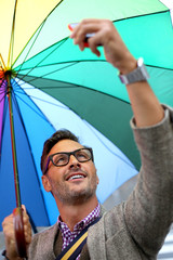 Man in town with rainbow umbrella