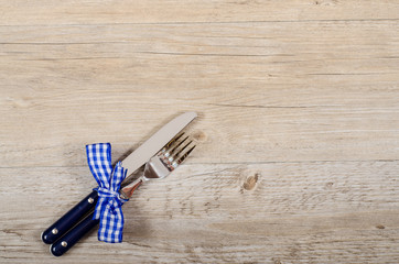 Blaue Messer und Gabel mit karierter Schleife auf einem Tisch