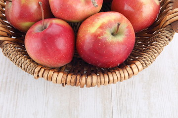 close up of basket with apples on wooden table