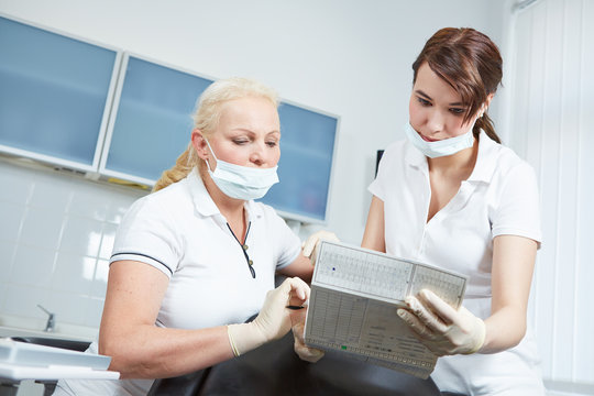 Dentist and dental assistant reading medical records