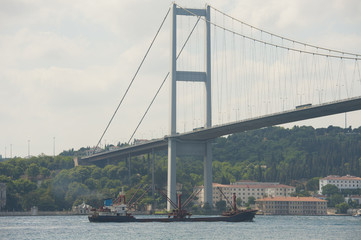 Large ship under a suspension bridge on river