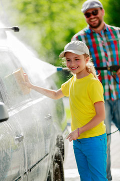Carwash - young girl helping father to wash car.