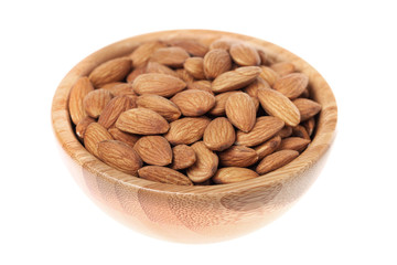 Almonds in a brown wooden bowl isolated on white background