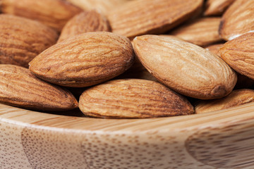 Closeup of almonds in a brown wooden bowl