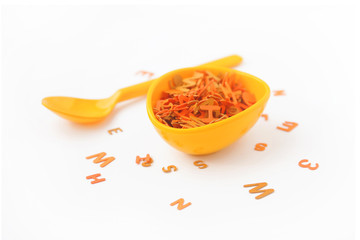 Yellow gravy boat and spoon with letters on white background