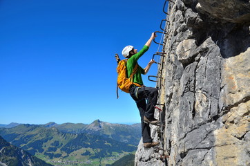 Kletterer an Leiter an Felswand, Klettersteig