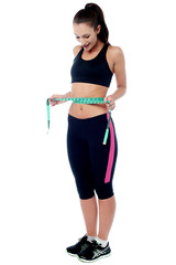 Slim fit woman measuring her waist