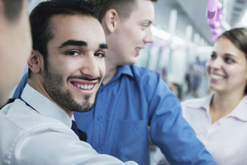 Obraz premium Portrait of young smiling businessman standing on the subway, looking at camera 