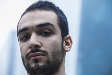 Fototapeta premium Portrait of serious young businessman, outdoors, business district, close-up