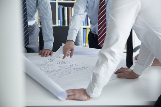 Two architects discussing over a blueprint in the office, mid section