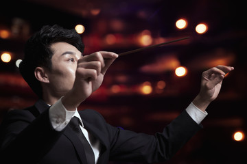 Young conductor with baton raised at a performance 