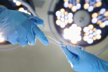 Close-up of gloved hands passing the surgical scissors, operating room, hospital - obrazy, fototapety, plakaty