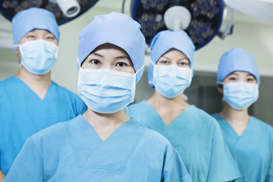 Team of surgeons wearing surgical masks in the operating room, looking at camera