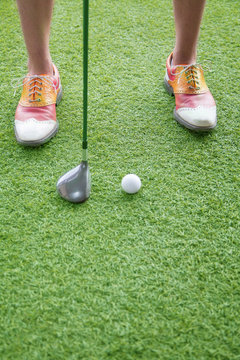 Close up on feet and golf club getting ready to hit a golf ball