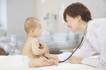 Doctor checking baby's heart beat with a stethoscope in the doctors office