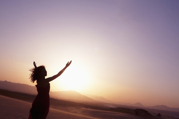 Fototapeta na wymiar Serene young woman with arms outstretched doing yoga in the desert in China, Silhouette