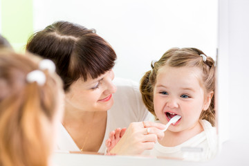 Obraz na płótnie Canvas mother kid brushing kid teeth