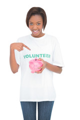 Smiling woman pointing at her piggy bank