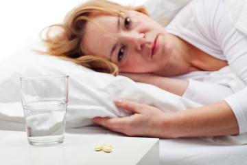 Obraz na płótnie Canvas Taking pills - woman laying in bed