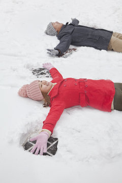 Young couple laying in snow making snow angels