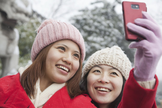 Two friends taking picture with cell phone in snow