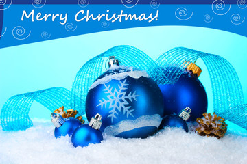 Beautiful blue Christmas balls in snow on blue background