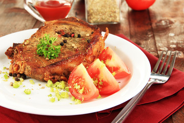 Piece of fried meat on plate on wooden table close-up