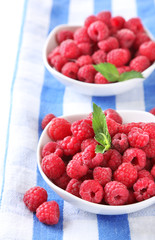 Ripe sweet raspberries in bowls, isolated on white