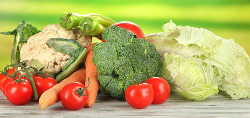 Fresh vegetables in basket on wooden table on natural