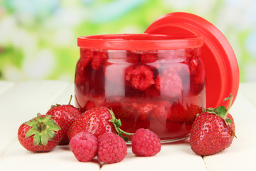 Home made berry jam on wooden table on bright background