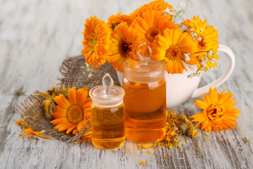 Medicine bottles and calendula flowers on wooden background