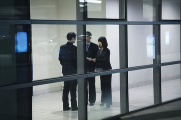   Three business people meeting, seen through glass wall