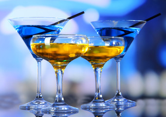 Glasses of cocktails on bright background
