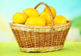 Ripe lemons in wicker basket on table on bright background