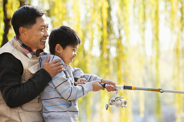 Father and son fishing together at lake