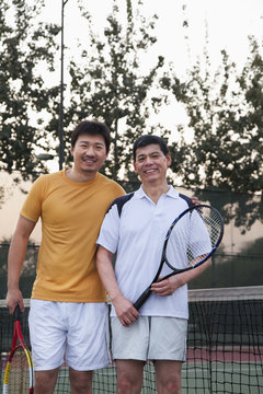 Father and mature son playing tennis, portrait