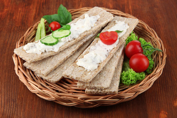 Tasty crispbreads with vegetables on wooden background