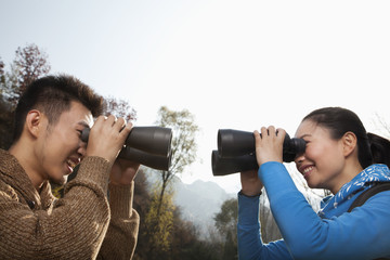 Young couple looking at each other through binoculars