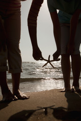 Silhouette of mother and daughter picking up a starfish on the beach