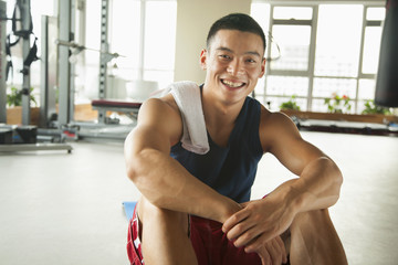 Young man sitting in the gym, portrait