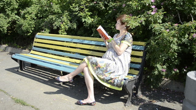 Pregnant woman reading book on the bench