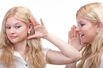 society gossip - two happy young girlfriends talking white backg