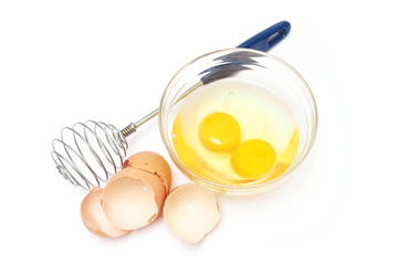 Fototapeta na wymiar whisk and eggs in a bowl on white background