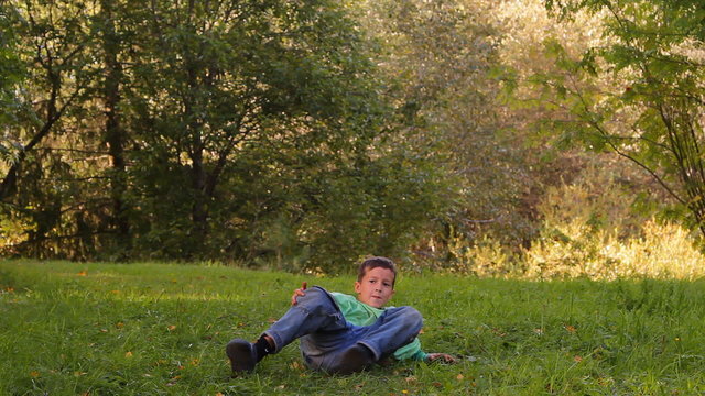 мальчик танцует, кувыркается, прыгает на траве