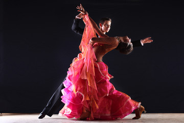 Latino dancers in ballroom against black background