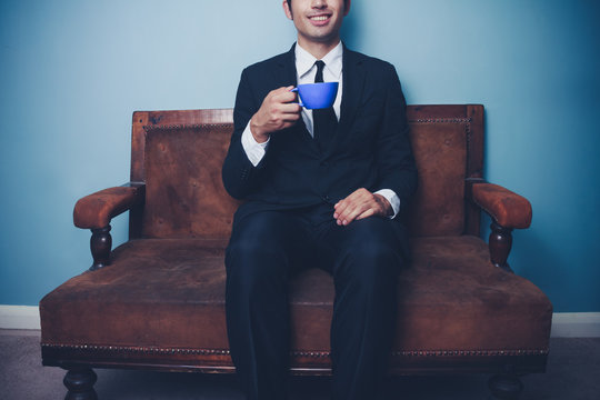 Happy young businessman drinking coffee